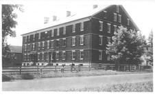 SA0379 - Photo of a large brick building and fence. Identified on the back.